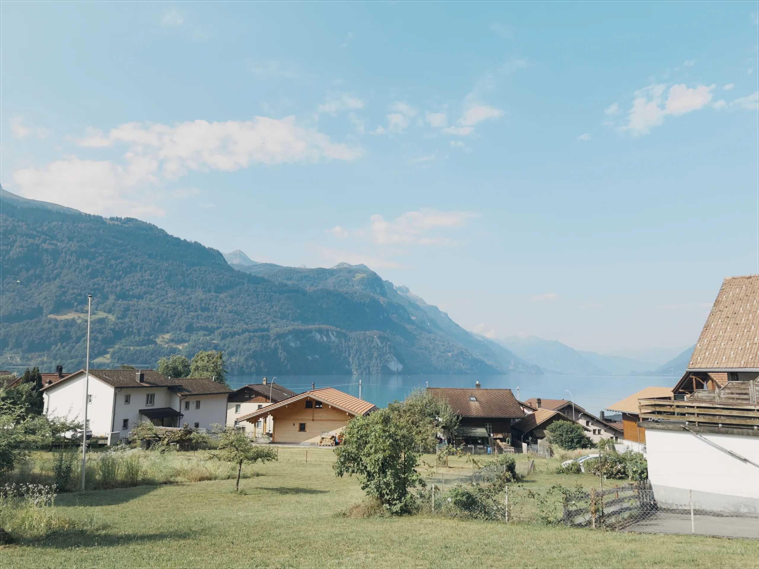 Homes in Brienz overlooking the lake and mountains beneath a pale blue sky.