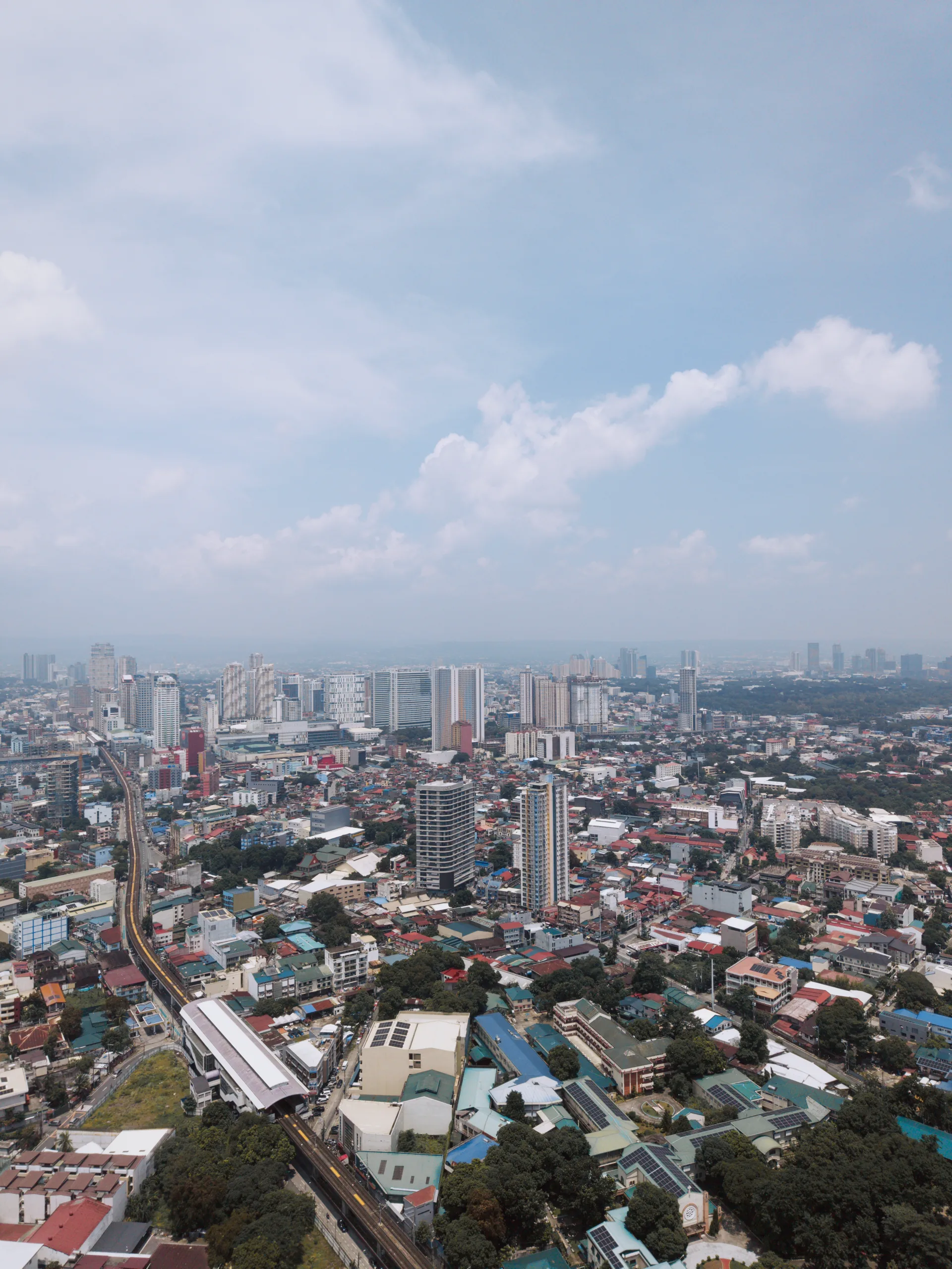 A high aerial view across a dense city beneath towering white clouds.