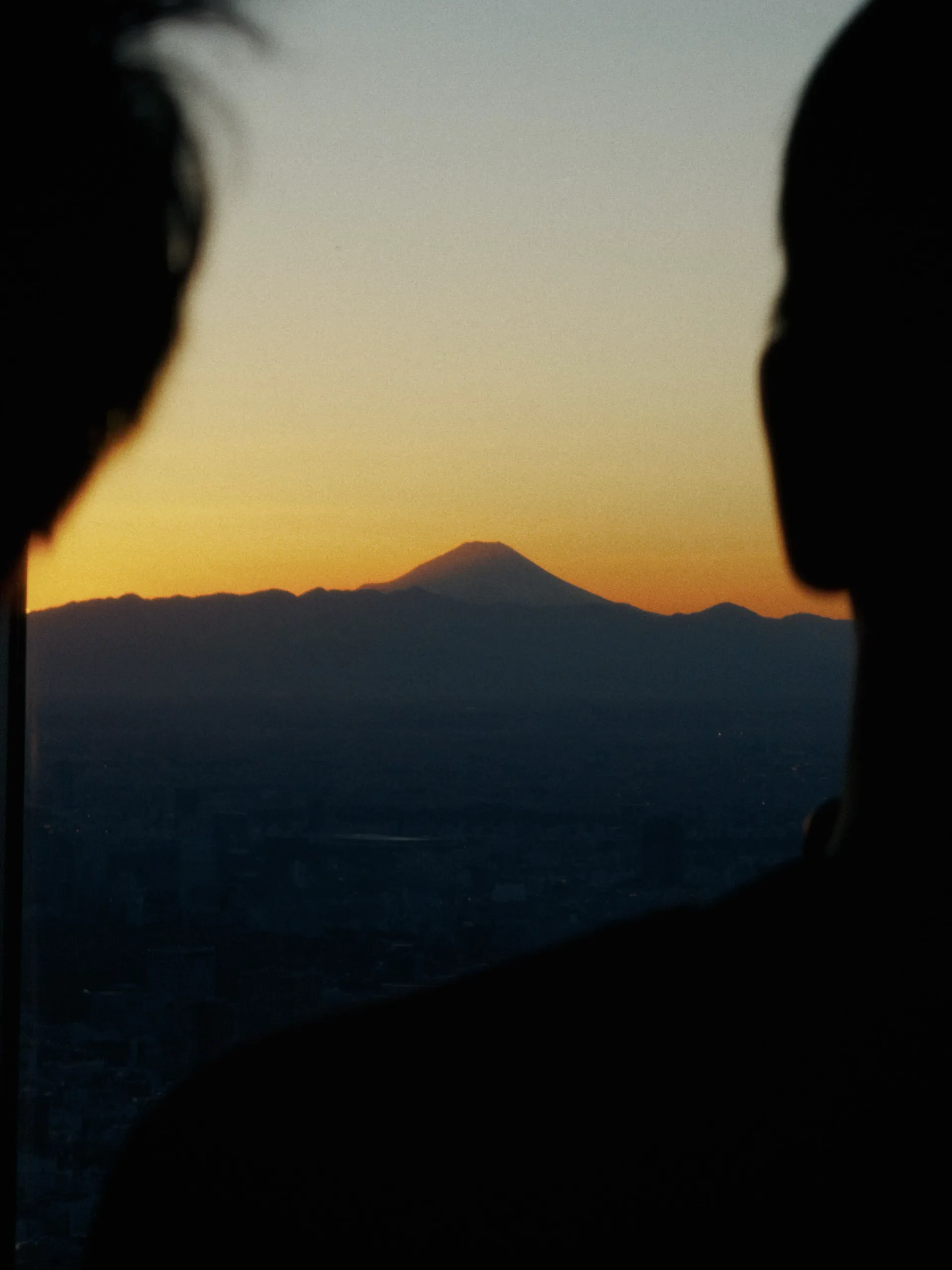 Mount Fuji at sunset framed by dark silhouettes.